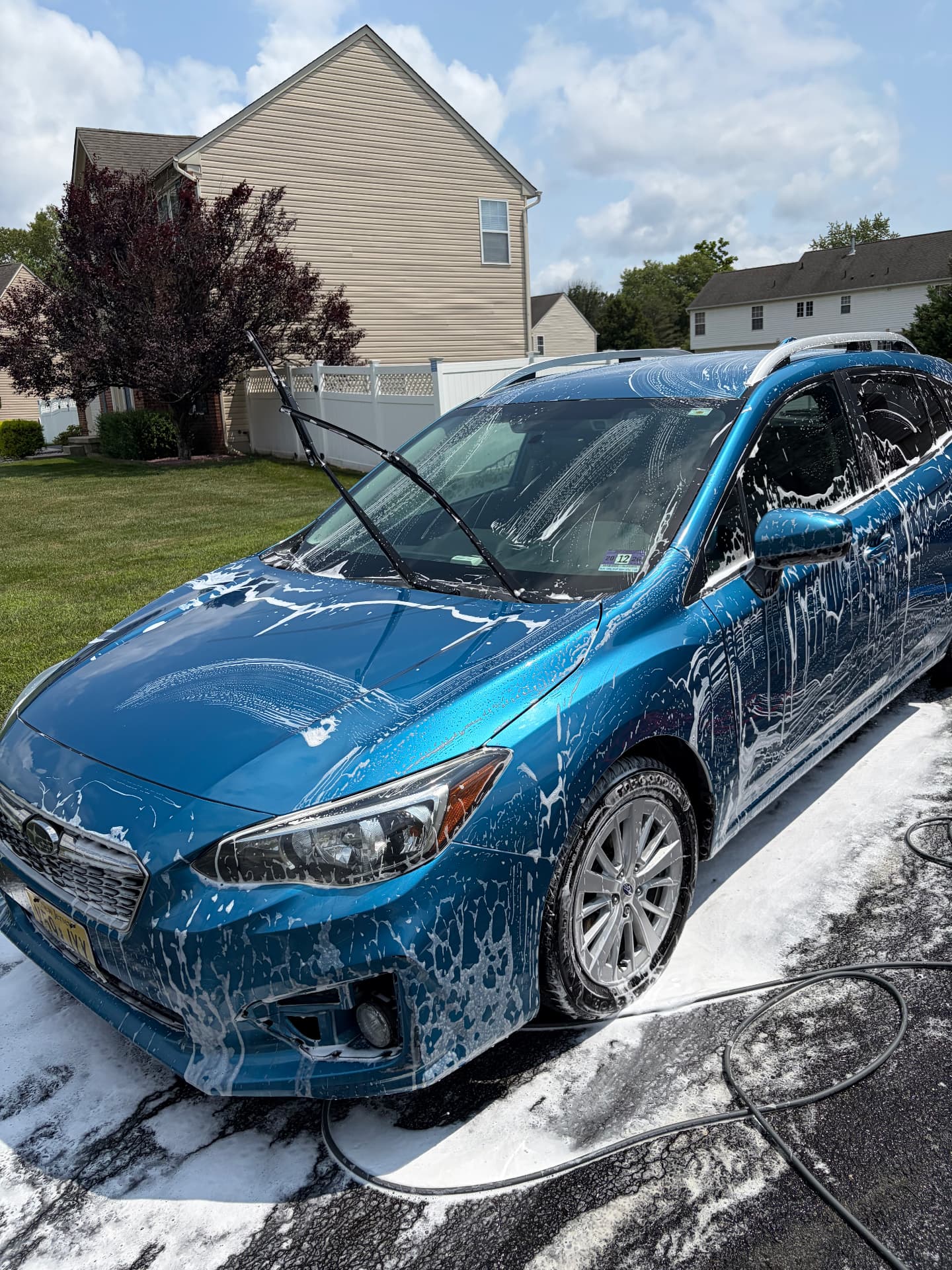 Blue Subaru Impreza covered in foam during a hand wash